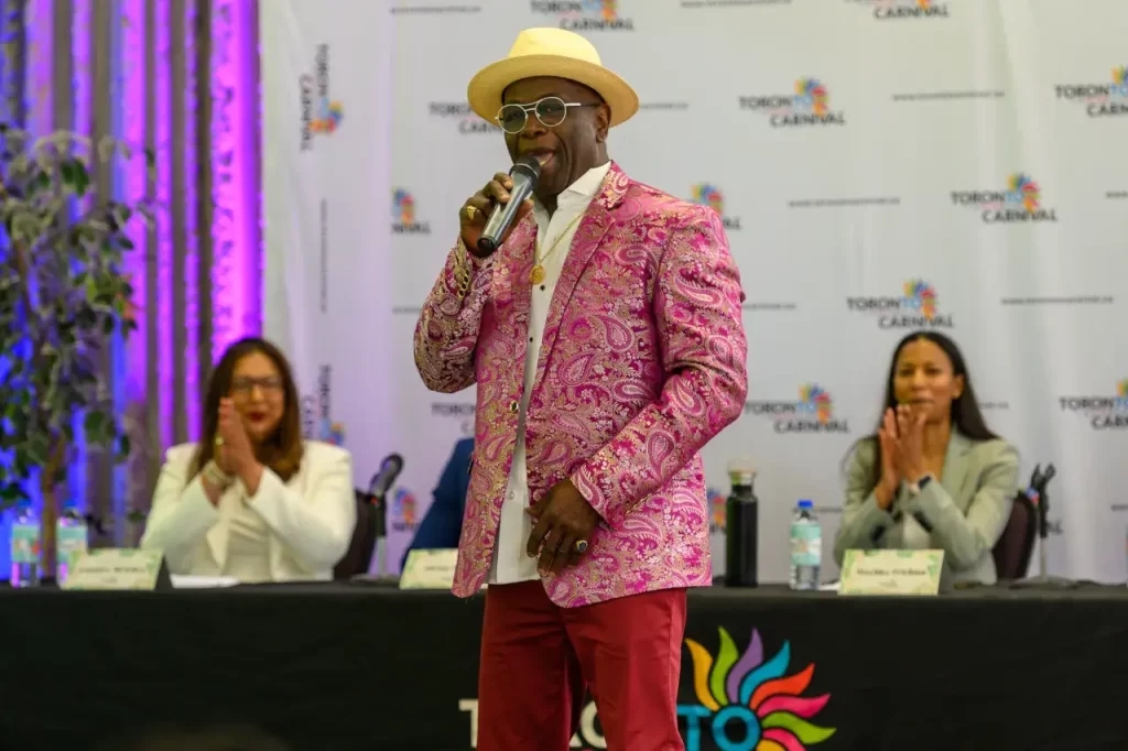 Soca singer performing at the Toronto Caribbean Carnival 2023 launch event, with festival executives in the background, encapsulating the vibrant spirit of the Caribbean.